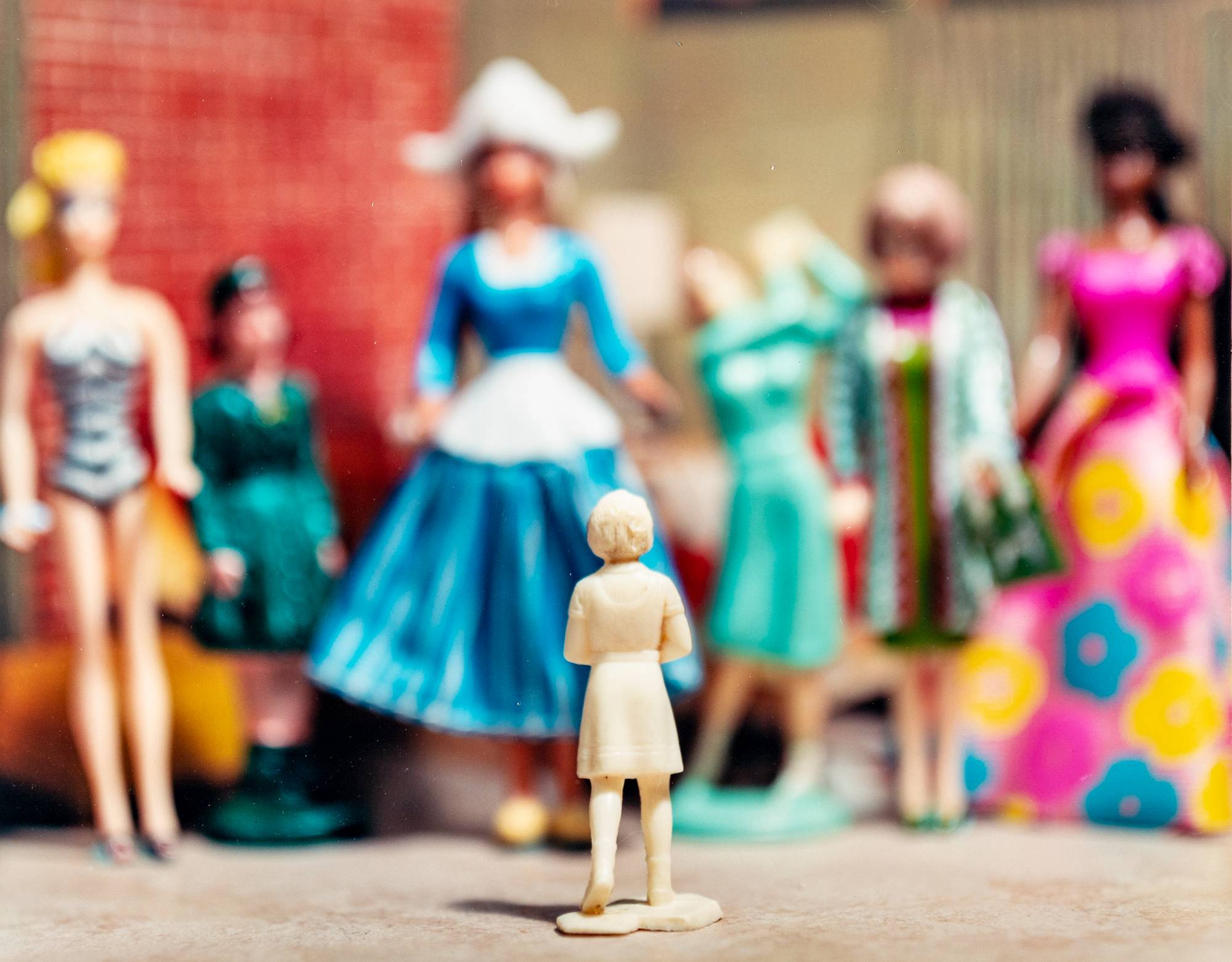 small female figurine in focus standing with back facing in front of many other female figurines in background out of focus